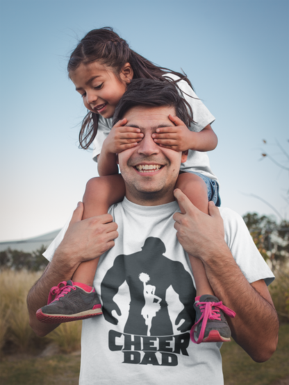 Smiling man wearing a white adult unisex t-shirt with Hulk "Cheer Dad" logo gives his daughter a ride on his shoulders as she covers his eyes with her hands